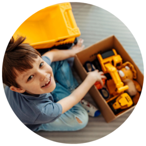 young boy smiling with box of toys